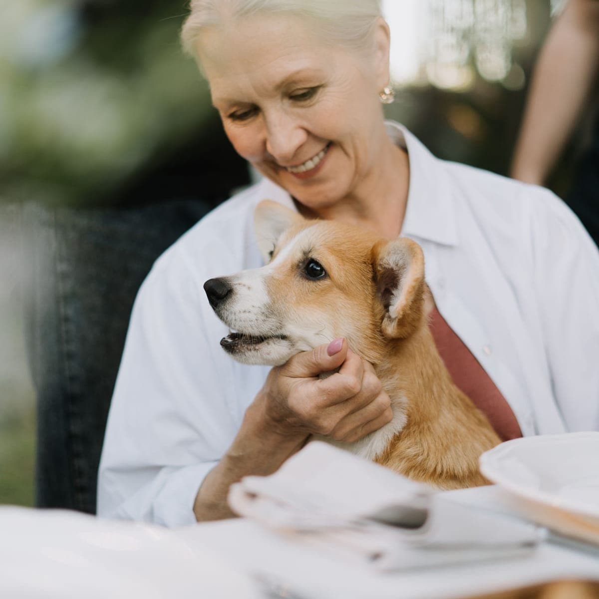 A smiling owner hugging her corgi